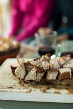 grilled meat cut into slices, on wooden board