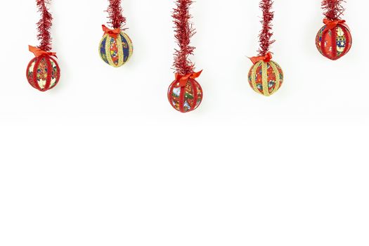 Christmas copy space: five Christmas baubles made by hand with the decoupage technique hung from top with a red shiny garland on white background