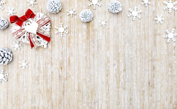 Flat lay shabby Christmas copy space with white wooden snowflakes, white pine cones and a white wooden decorative heart in the upper left corner on light wooden background