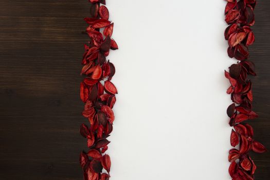 Flat lay Christmas copy space with dark wood on one side and red petals bordering a white background