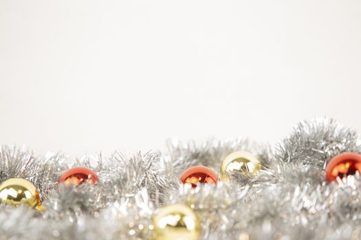 Christmas copy space with red and gold bright baubles in silver decorative chain on bottom on white background and bokeh effect