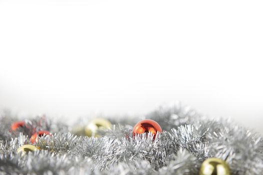 Christmas copy space with red and gold bright baubles in silver decorative chain on bottom on white background and bokeh effect