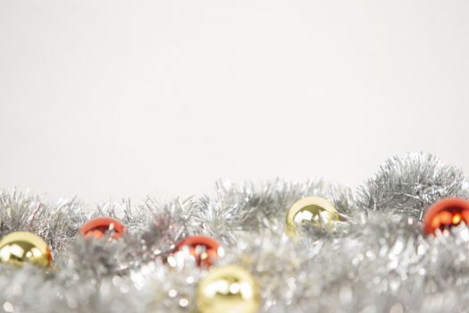 Christmas copy space with red and gold bright baubles in silver decorative chain on bottom on white background and bokeh effect