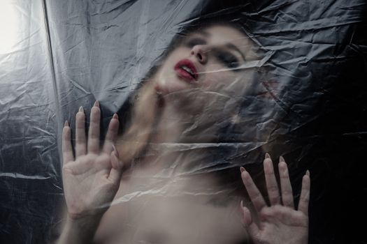 Young beauty sad woman trapped behind a plastic sheet as protection against COVID-19. Nicely fits for book cover