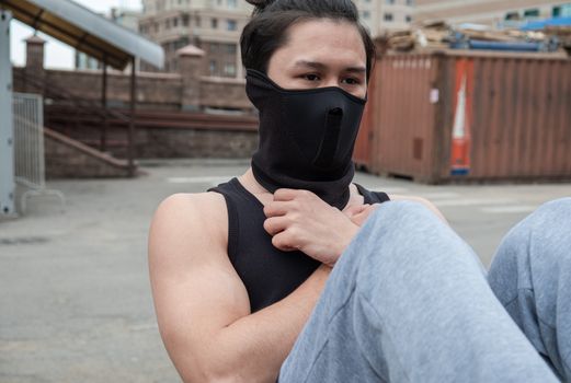 The guy is doing sport exercise, in a black T-shirt and mask, in quarantine