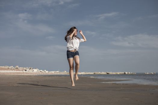 Attractive Girl Jumping on the Beach Having Fun, Summer vacation holiday Lifestyle. Happy women jumping freedom on white sand.