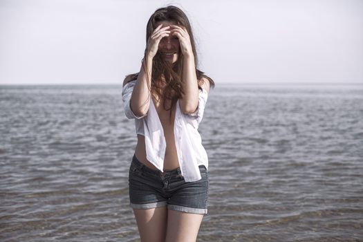 Smiling young woman enjoying her summer vacation on the beach. Beautiful female model having fun on the sea shore.