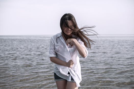 Smiling young woman enjoying her summer vacation on the beach. Beautiful female model having fun on the sea shore.