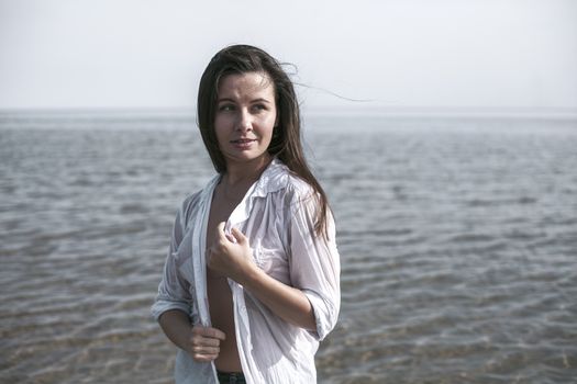 Smiling young woman enjoying her summer vacation on the beach. Beautiful female model having fun on the sea shore.