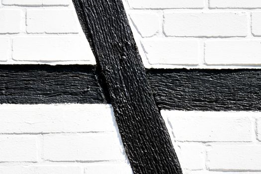 Detail of the side wall of a half-timbered house with black wooden beams and whitewashed walls of mud bricks, Germany