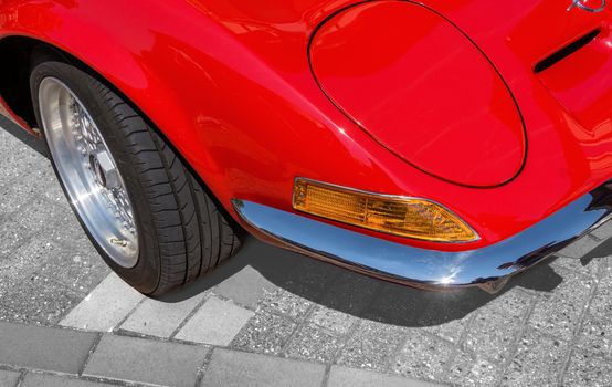 Detail view, from the right front corner of a red sports car with folding headlights, indicators,. bumper and a part of the front wheel, Germany