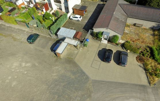 Obliquely taken aerial view of a commercial enterprise on an area of concrete and asphalt with an office building and a warehouse, Germany