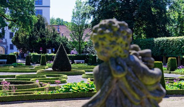 Baroque garden with a deliberately blurred stone figure in the foreground, germany