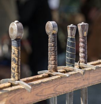 Handles of historical swords hung in a row on a medieval market, Germany