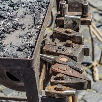 Historical tools of a blacksmith at a medieval market such as hammer, chisel, broach, chisel, beating plate, pestle, axe, pliers, axe, iron, in Germany