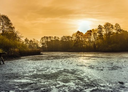 Muddy drained pond at dawn, landscape photo with dramatic development, germany