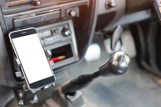 Cropped shot view The driver uses the phone while driving. Modern smart phone with round edges. Isolated screen for mockup. Car navigation display in background. 