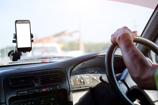 Cropped shot view The driver uses the phone while driving. Modern smart phone with round edges. Isolated screen for mockup. Car navigation display in background. 