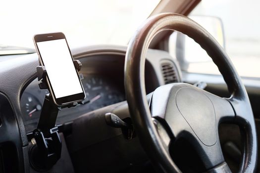 Cropped shot view The driver uses the phone while driving. Modern smart phone with round edges. Isolated screen for mockup. Car navigation display in background. 