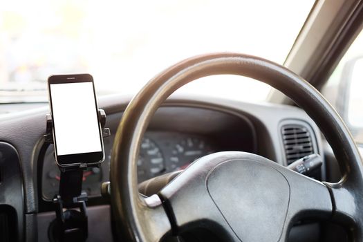 Cropped shot view The driver uses the phone while driving. Modern smart phone with round edges. Isolated screen for mockup. Car navigation display in background. 