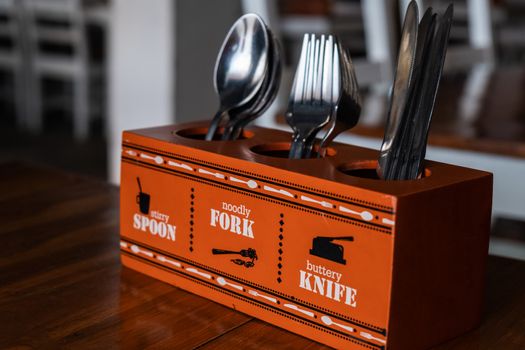 Stand with knives, forks and spoons in cafe on table