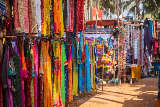 Indian bazaar benches with colorful saris and dresses, Day Market, Anjuna, Goa