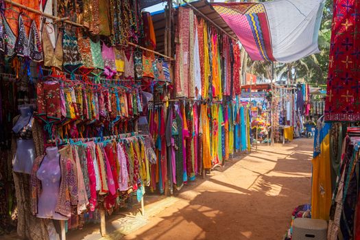 Indian bazaar benches with colorful saris and dresses, Day Market, Anjuna, Goa