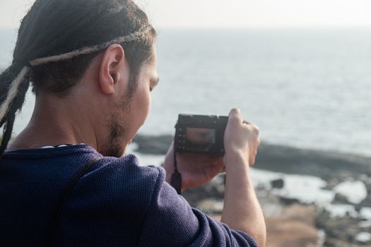 Young Asian photographer taking a picture from the top of a mountain, Northern Goa, India