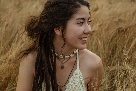Portrait Of Smiling Young Woman Sitting On Dry Grass