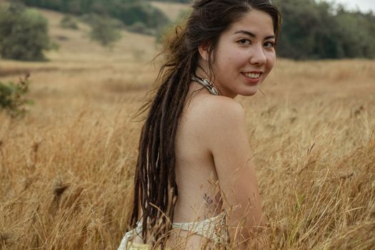 Portrait Of Smiling Young Woman Sitting On Dry Grass