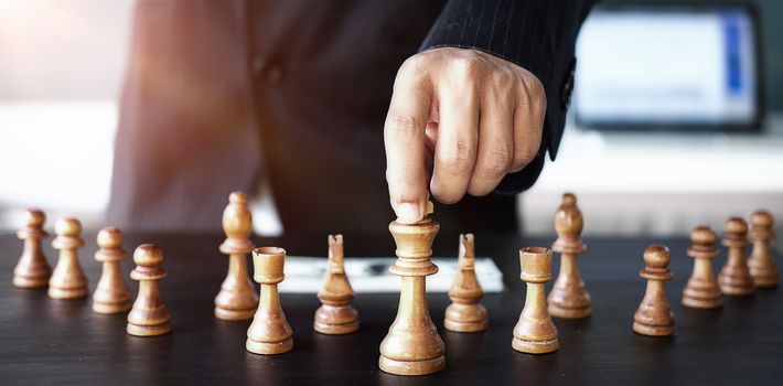 Businessman moving chess figure in competition success management or leadership concept 