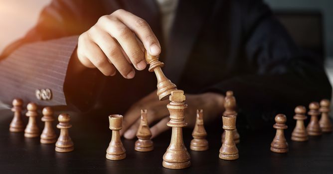 Businessman moving chess figure in competition success management or leadership concept 