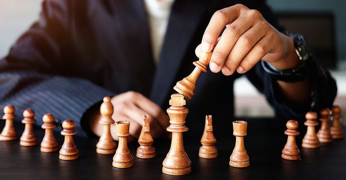 Businessman moving chess figure in competition success management or leadership concept 