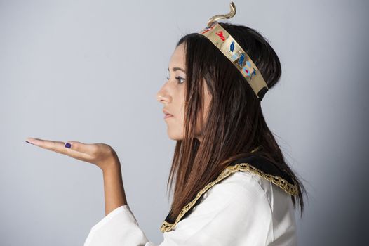 Beautiful young brunette girl posing in studio wearing egyptian clothing fancy dress isolated on blue background