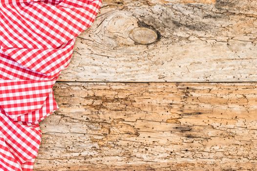Rustic old wooden table surface with red checkered cloth, top view