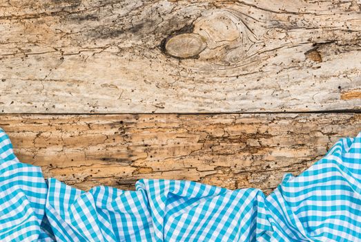 Rustic old wooden table surface with blue checkered cloth, top view