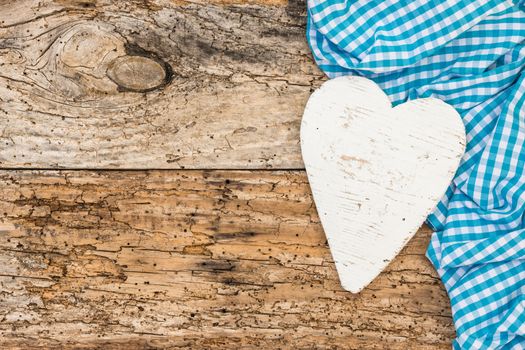 Rustic white heart with light blue fabric on vintage wood background with copy space