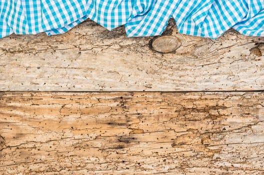 Old wooden table surface with rustic blue checkered cloth, top view