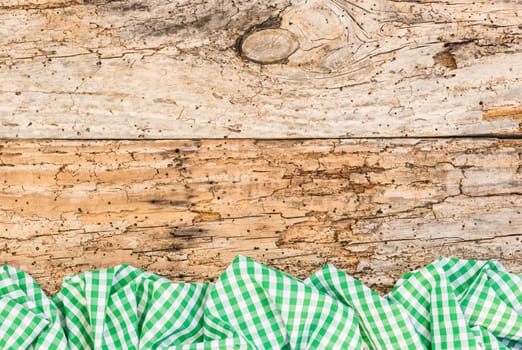 Old wooden table surface with rustic green checkered cloth, top view