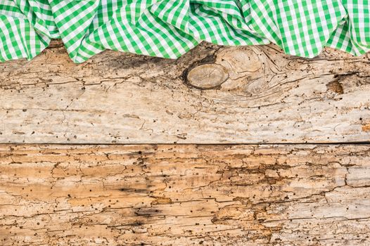 Rustic old wooden table surface with green checkered cloth, top view