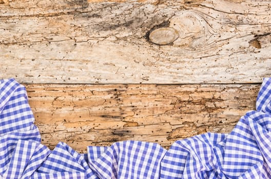 Old wooden table surface with rustic blue checkered cloth, top view