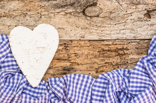 Rustic white heart with blue fabric frame on old wood with copy space