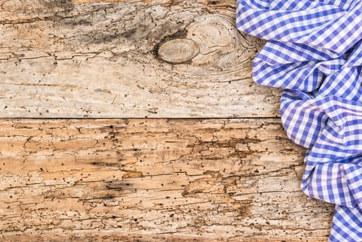 Old wooden table surface with rustic blue checkered cloth, top view