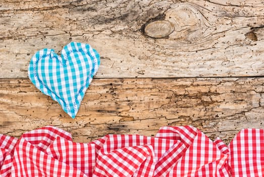 Blue fabric heart with red checked pattern frame on vintage wood with copy space