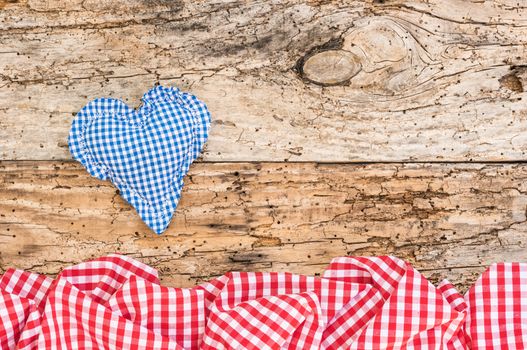 Blue heart with red fabric border on old wooden background with copy space