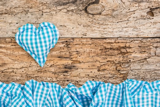 Rustic blue heart with fabric border on vintage wood background with copy space