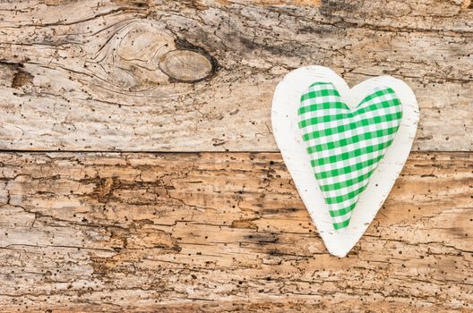 Green fabric heart on vintage wood background with copy space