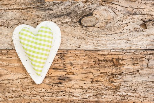Green fabric heart on old wooden background with copy space