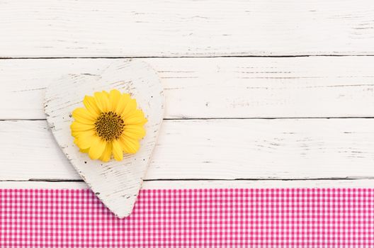 Rustic white wooden heart on white background with yellow flower and copy space