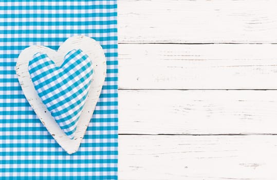 Rustic light blue fabric heart on white wood background with copy space